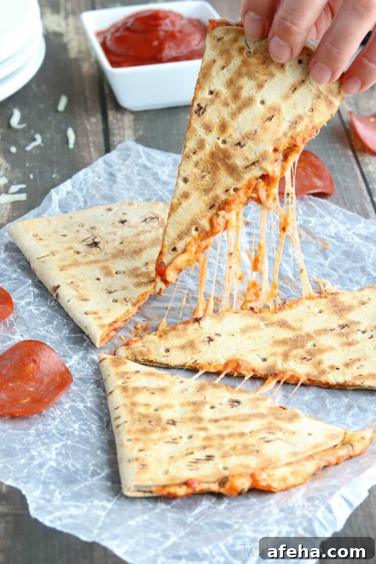 Hand picking up a quesadilla wedge with melty cheese strings.