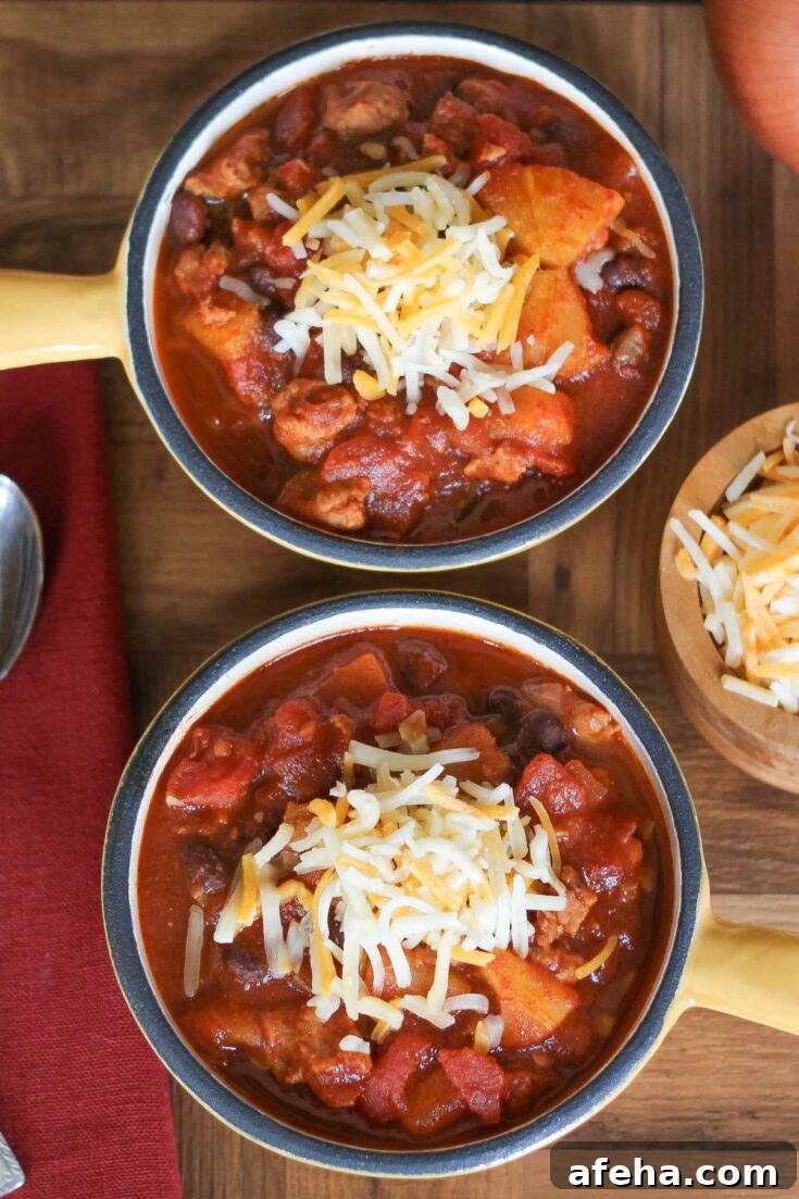 Two yellow crocks full of chili topped with shredded cheese.