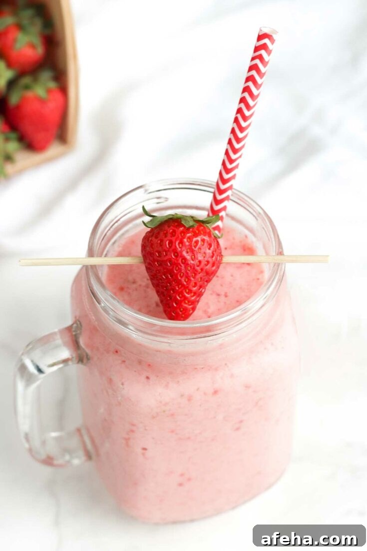 Smoothie in mason jar with strawberry on top.