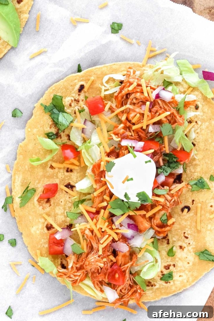 Taco laid open on white paper with chicken and toppings.