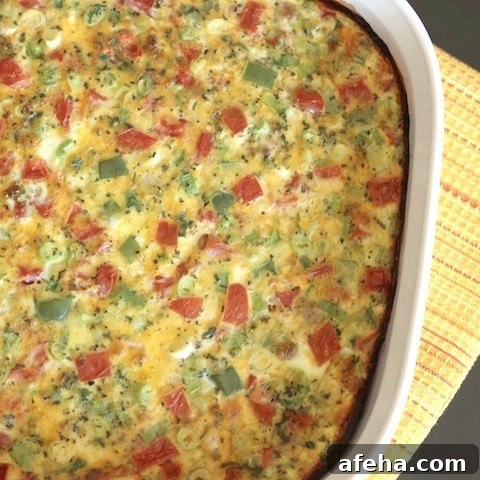 Part of an oval baking dish with finished egg casserole on a yellow striped cloth.