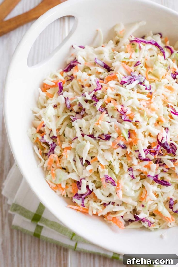 Serving bowl of coleslaw on a green-striped towel.