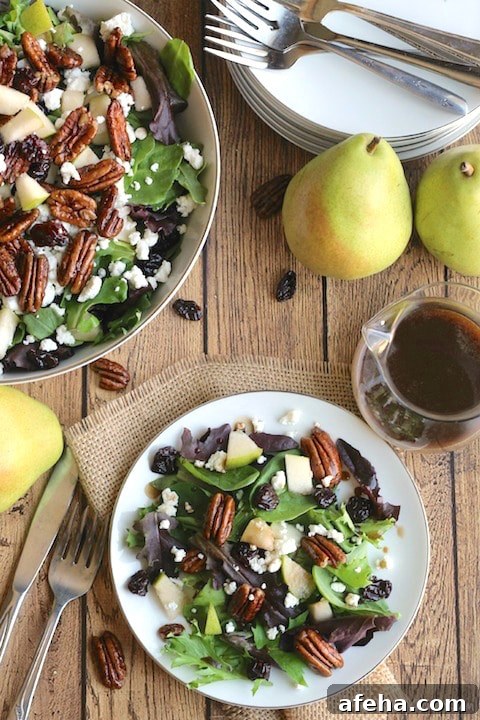 White plate filled with salad, pears and dressing.