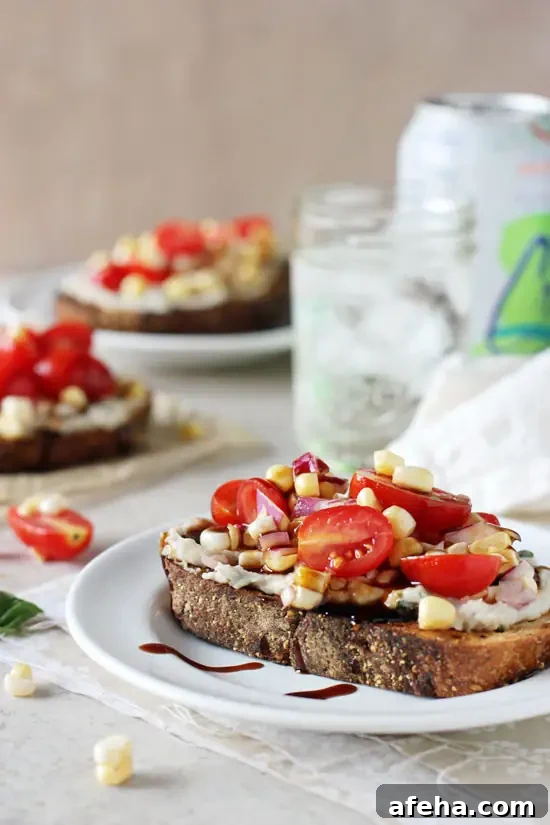 A Corn Tomato Sandwich on a white plate with sparkling water in the background.