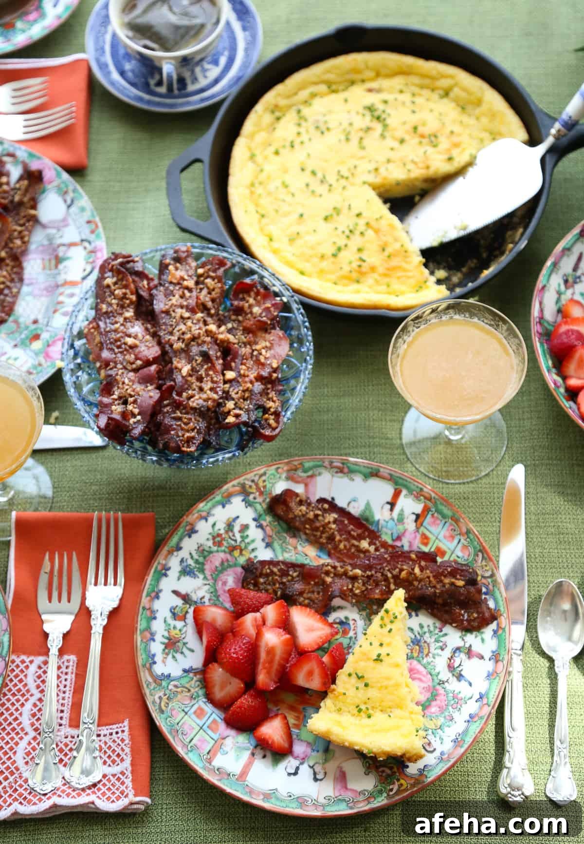 Praline-Crusted Candied Bacon — Sweet & Crunchy Bacon Recipe 9 table set with colorful china, orange lace napkins, and brunch food.