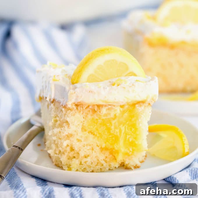 A piece of lemon poke cake garnished with lemon slices on a white plate