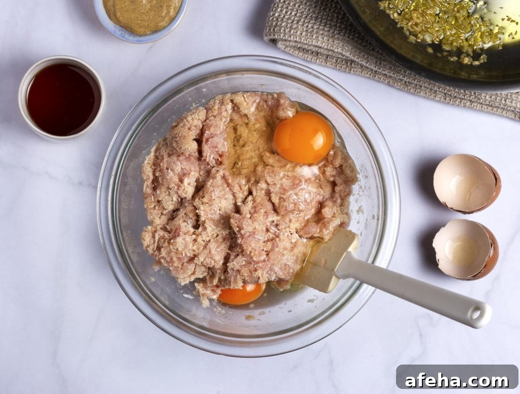 combined meat loaf ingredients in a glass mixing bowl with two eggs on top