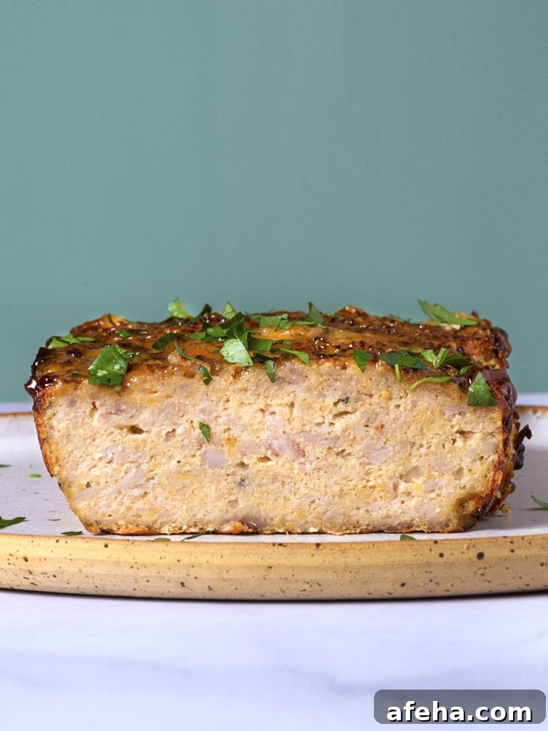 slices of chicken meatloaf on a wooden board with a green background