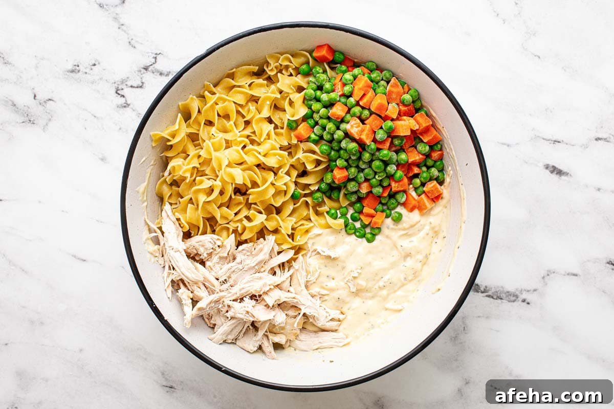Comforting Chicken Noodle Soup Casserole Recipe 5 Noodles, frozen veggies, shredded chicken, and creamy sauce.