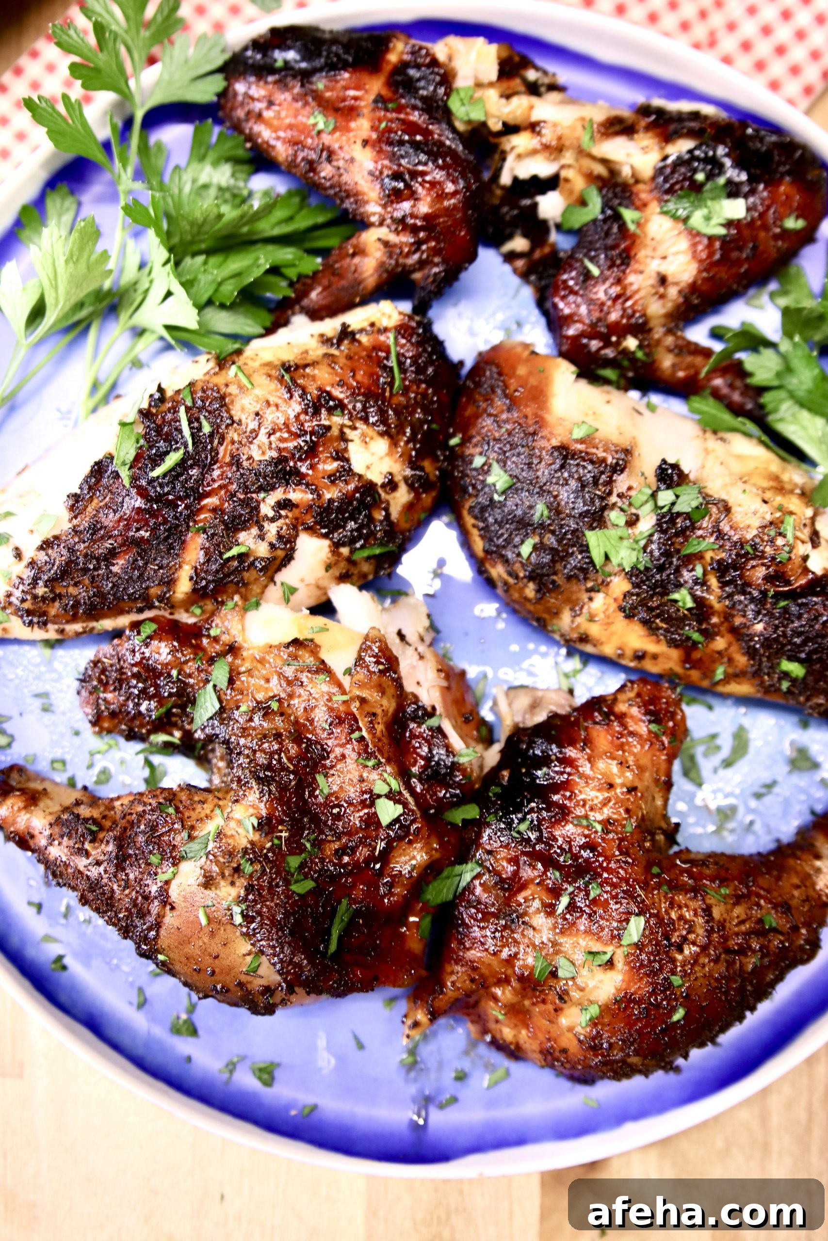 cut up grilled chicken on a blue plate with parsley garnish