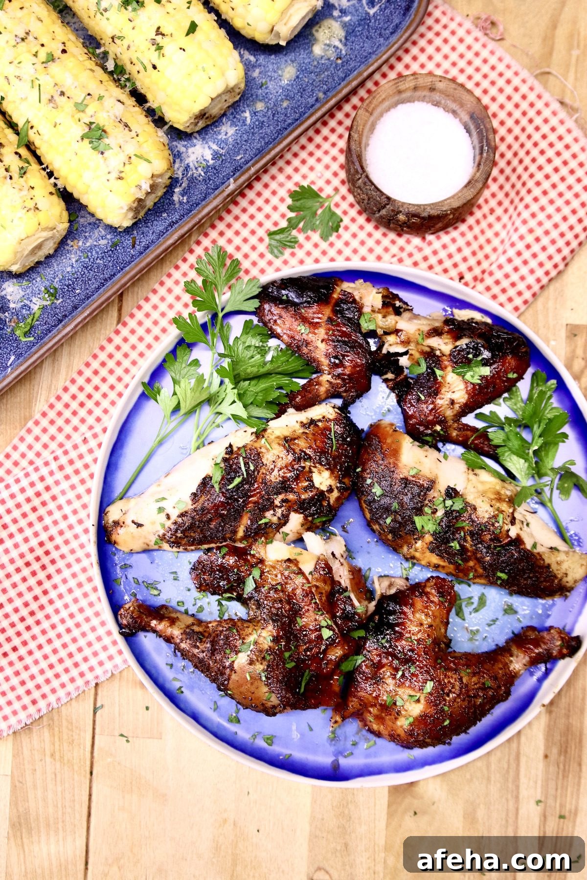 platter of grilled chicken pieces, corn on the cob on a platter