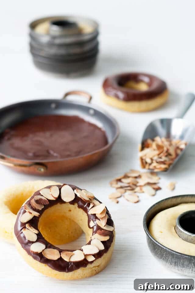 Image of making baked donuts in vintage donut pans, dipped in shallow dish of chocolate glaze and coated with sliced almonds in a scoop