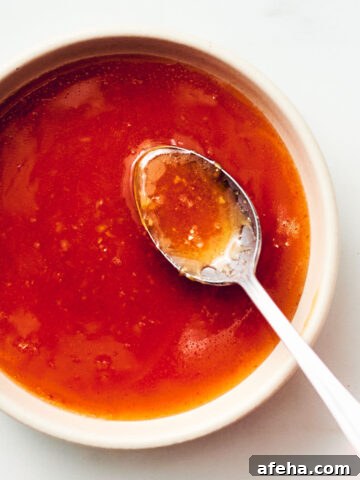 Easy honey sriracha sauce in a bowl with a spoon.