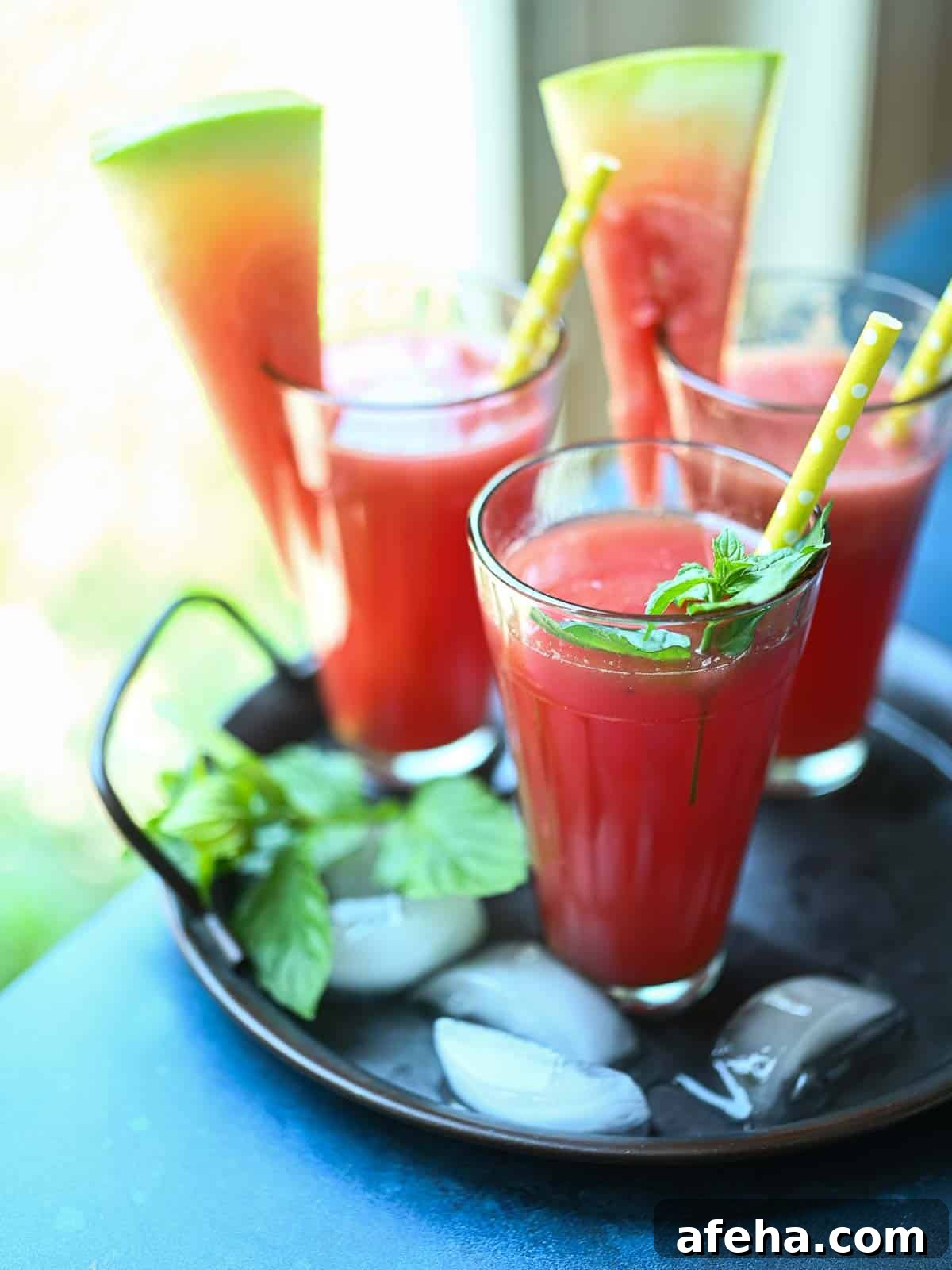 Three glasses on watermelon water on a tray by the window.