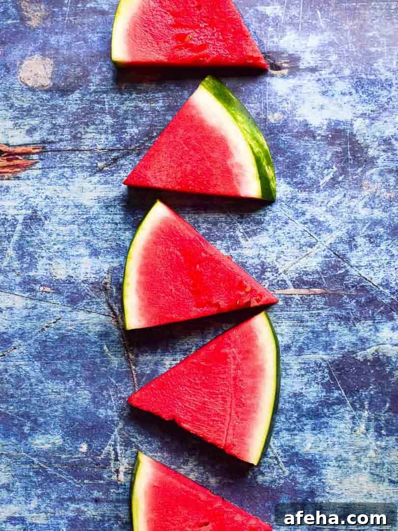 Overhead of sliced watermelon triangles on a blue surface.