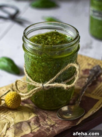 Roasted garlic pesto sauce in a clear jar on a wooden surface.