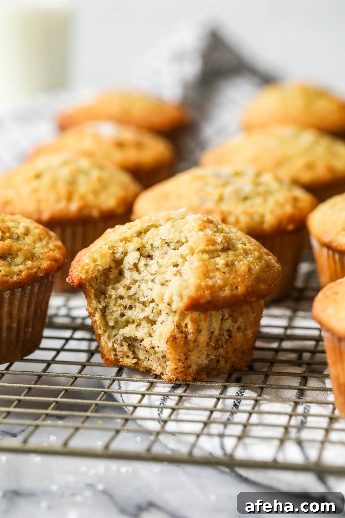 Bite missing from a sourdough banana muffin on a cooling rack.