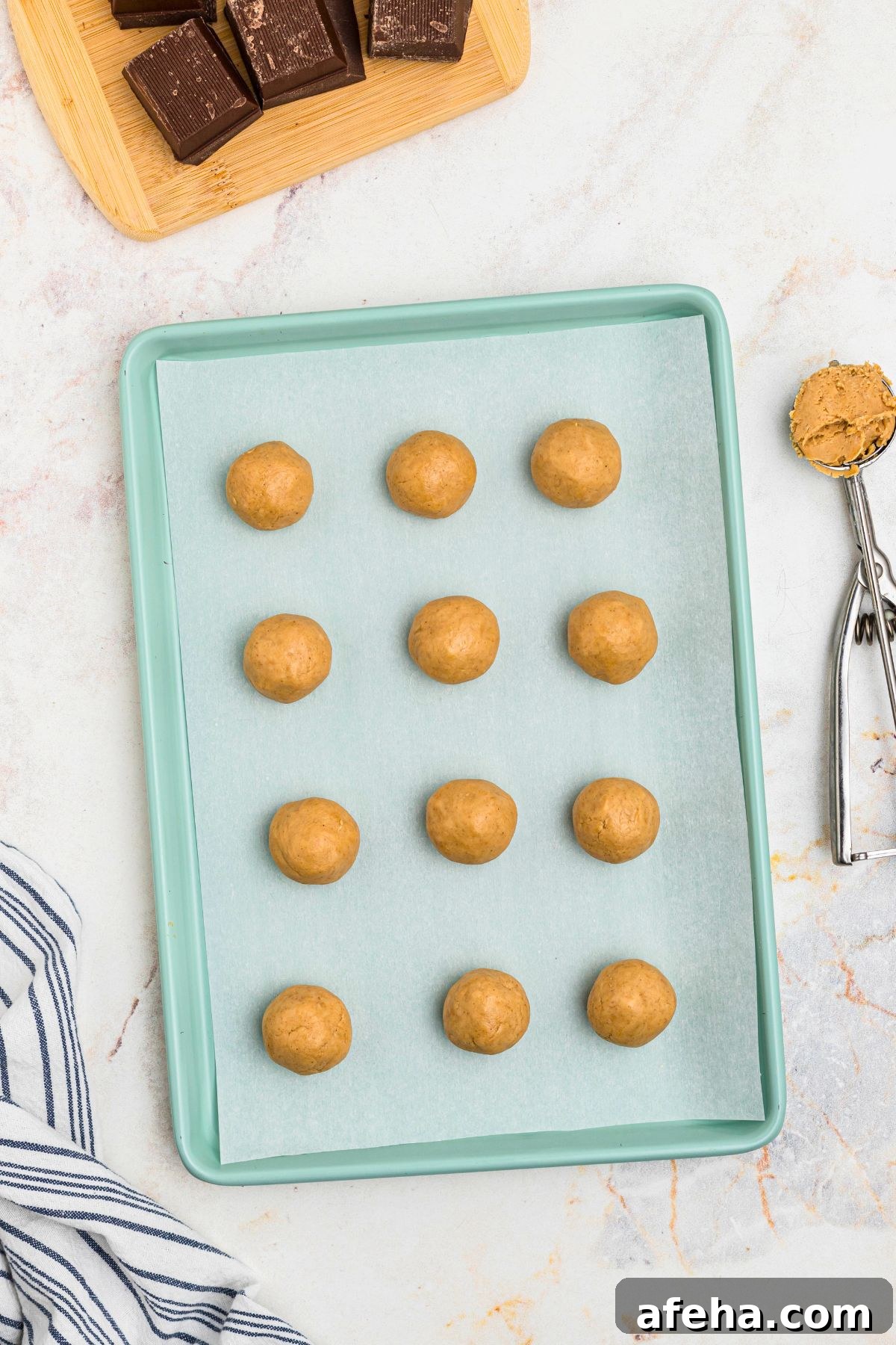 Scoops of peanut butter filling on a parchment paper lined sheet. 