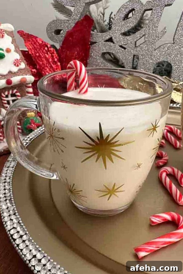 An eggnog brandy alexander cocktail on a golden platter, next to red candy canes.