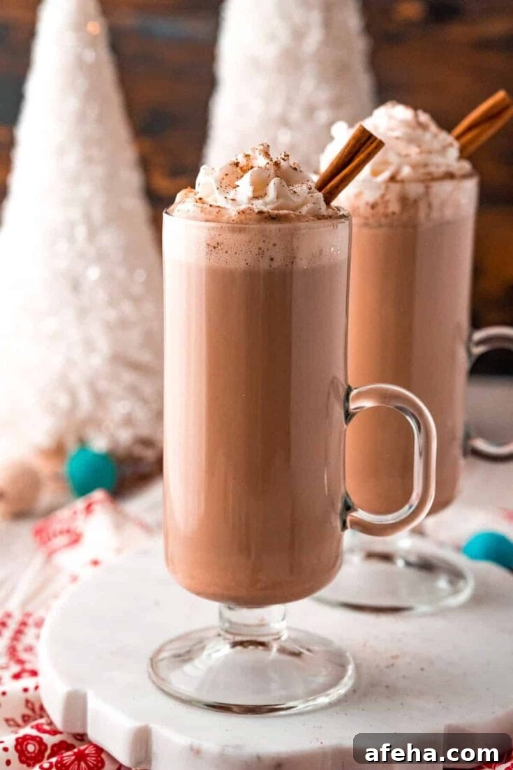 An eggnog hot chocolate topped with whipped cream and garnished with a cinnamon stick.