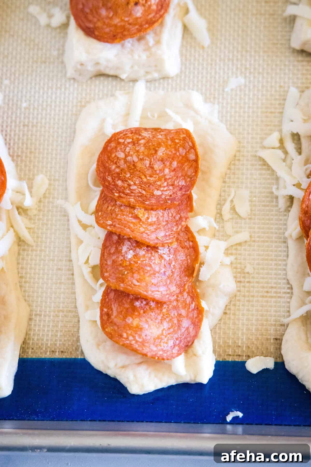Shredded mozzarella and pepperoni layered over rolled-out pizza dough on a baking sheet.