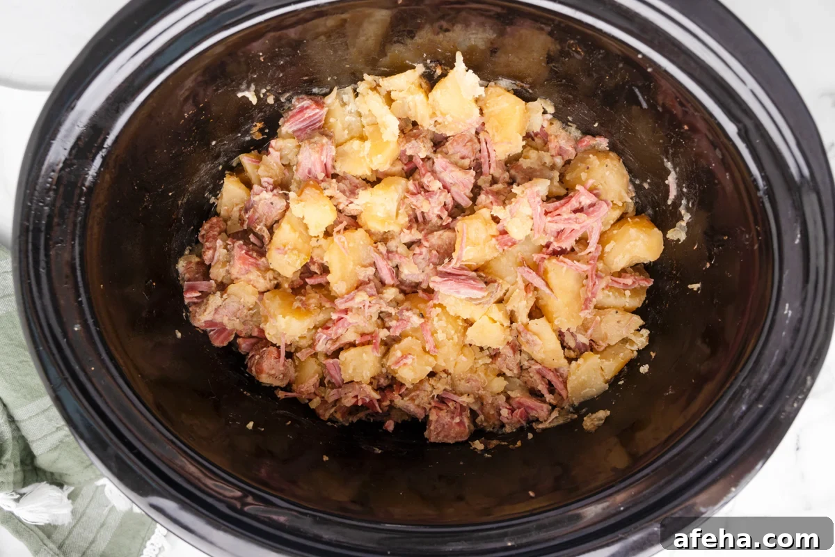 shredded corned beef and potatoes in a slow cooker.