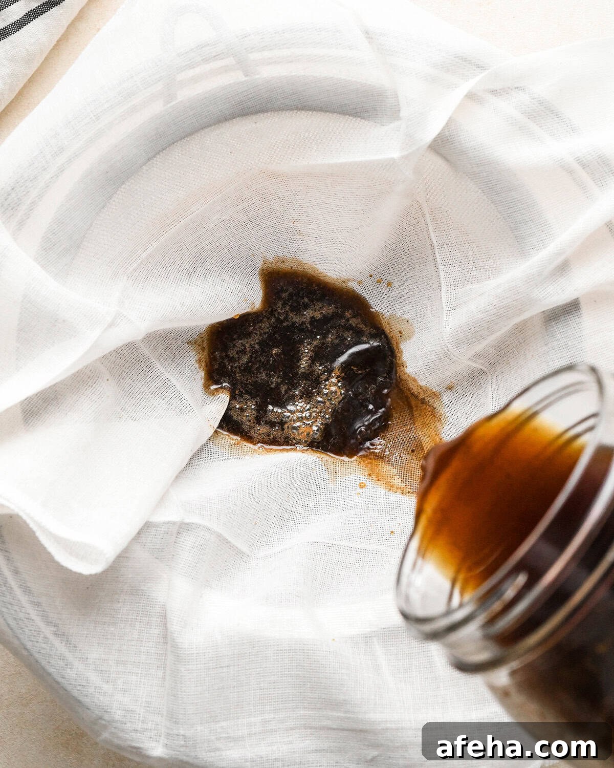 straining coffee grounds through a cheesecloth and fine mesh strainer