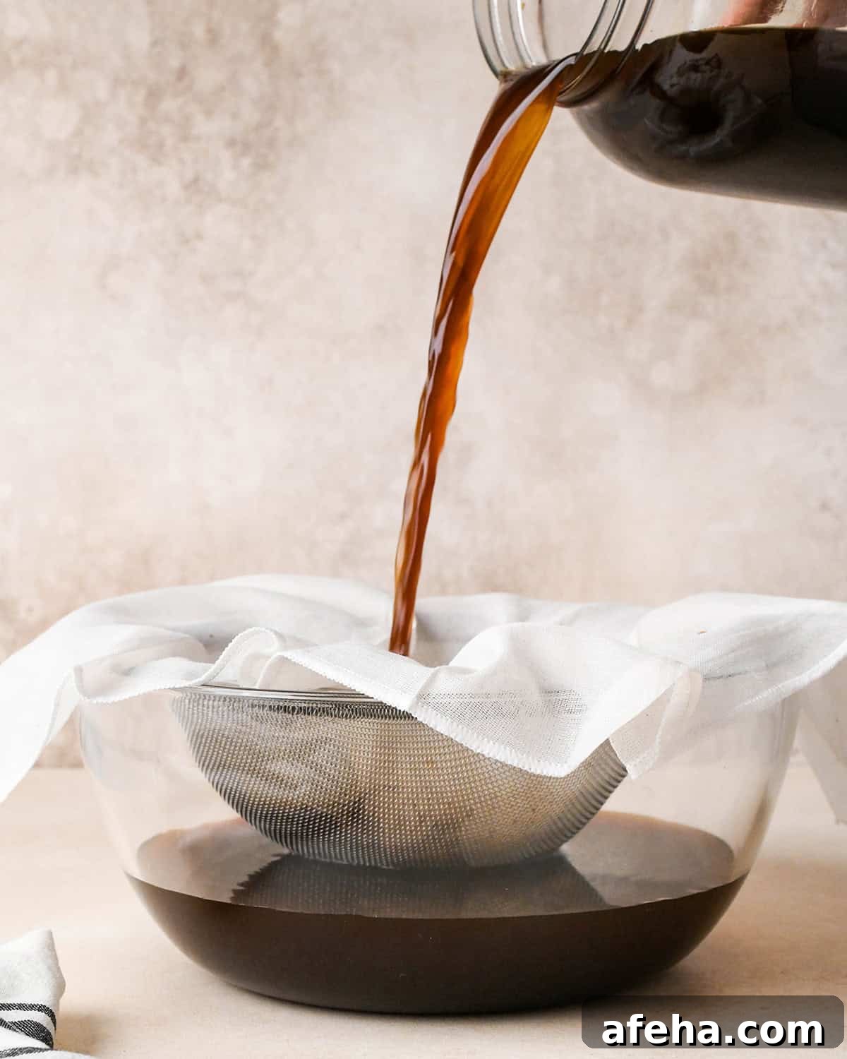 straining coffee grounds through a cheesecloth and fine mesh strainer