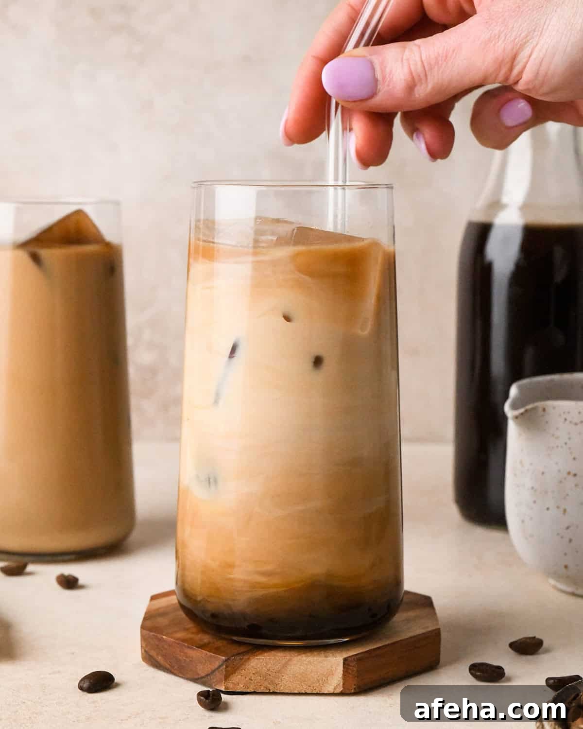 a hand stirring a glass of Cold Brew Coffee with a straw