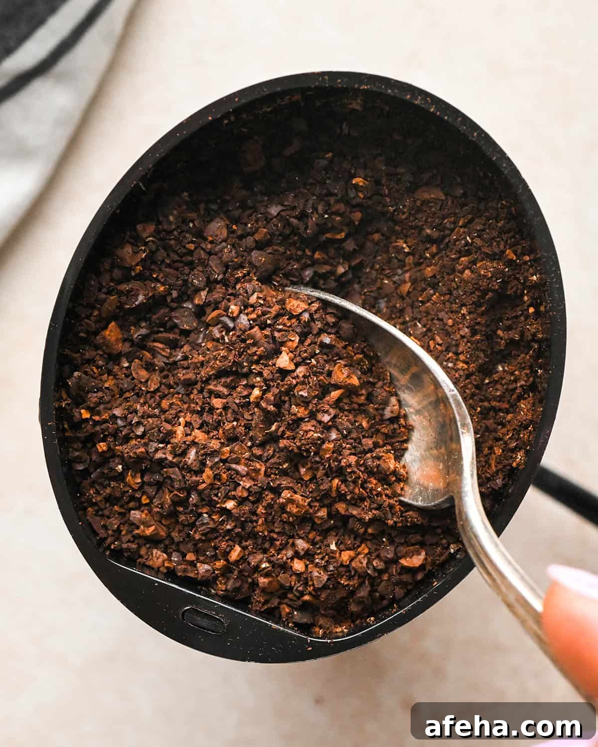 coarsely ground coffee in a grinder with a spoon to make cold brew coffee
