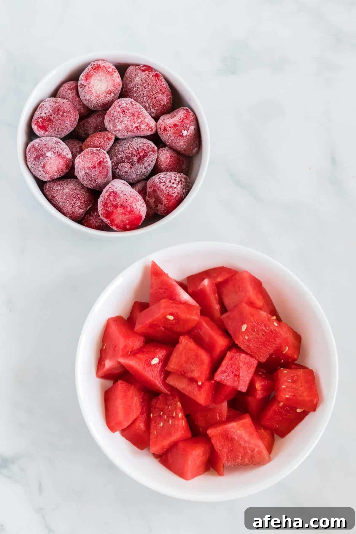 fresh watermelon and frozen strawberries in white bowls