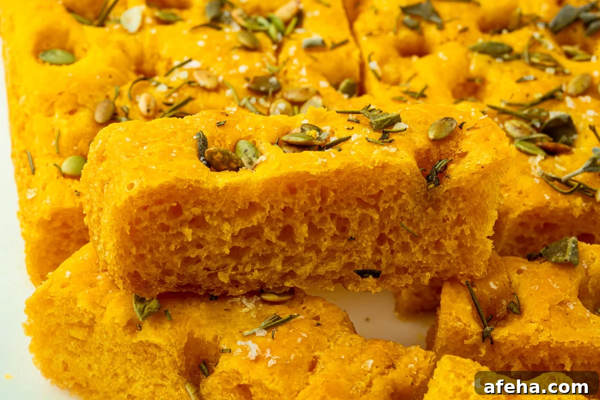 Thick slice of gluten-free pumpkin focaccia highlighting its airy interior and crisp edges.