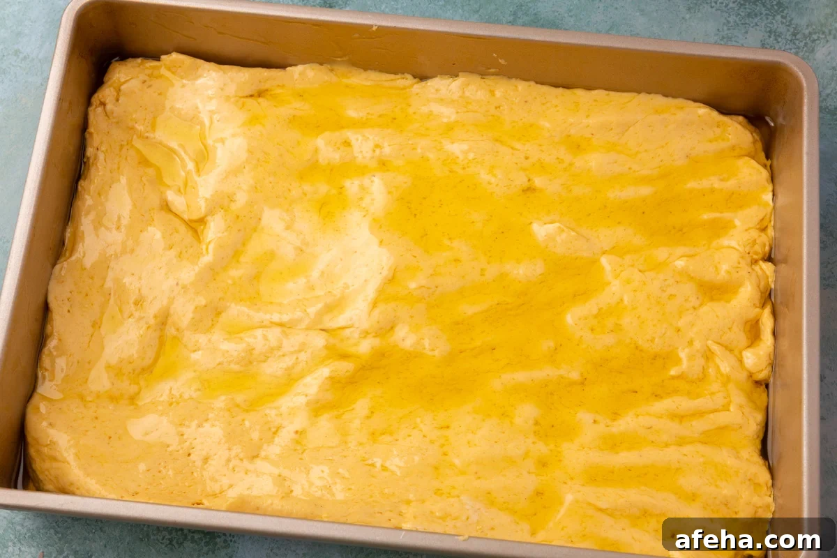 Pumpkin focaccia dough spread in the pan and drizzled with olive oil.