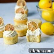 moist lemon drizzle cupcakes on a marble surface with lemon buttercream and dried lemons.