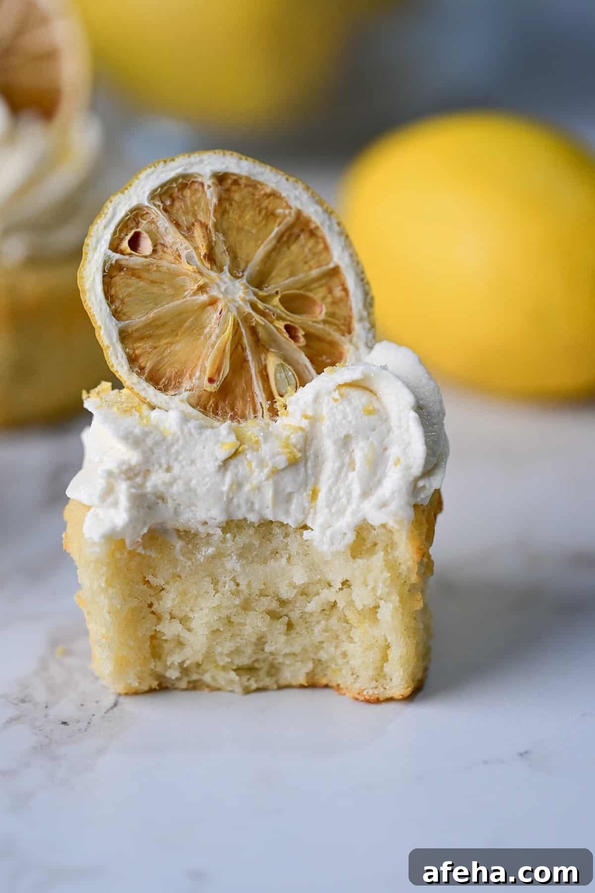 closeup view of lemon drizzle cupcake with a bite taken out of it.