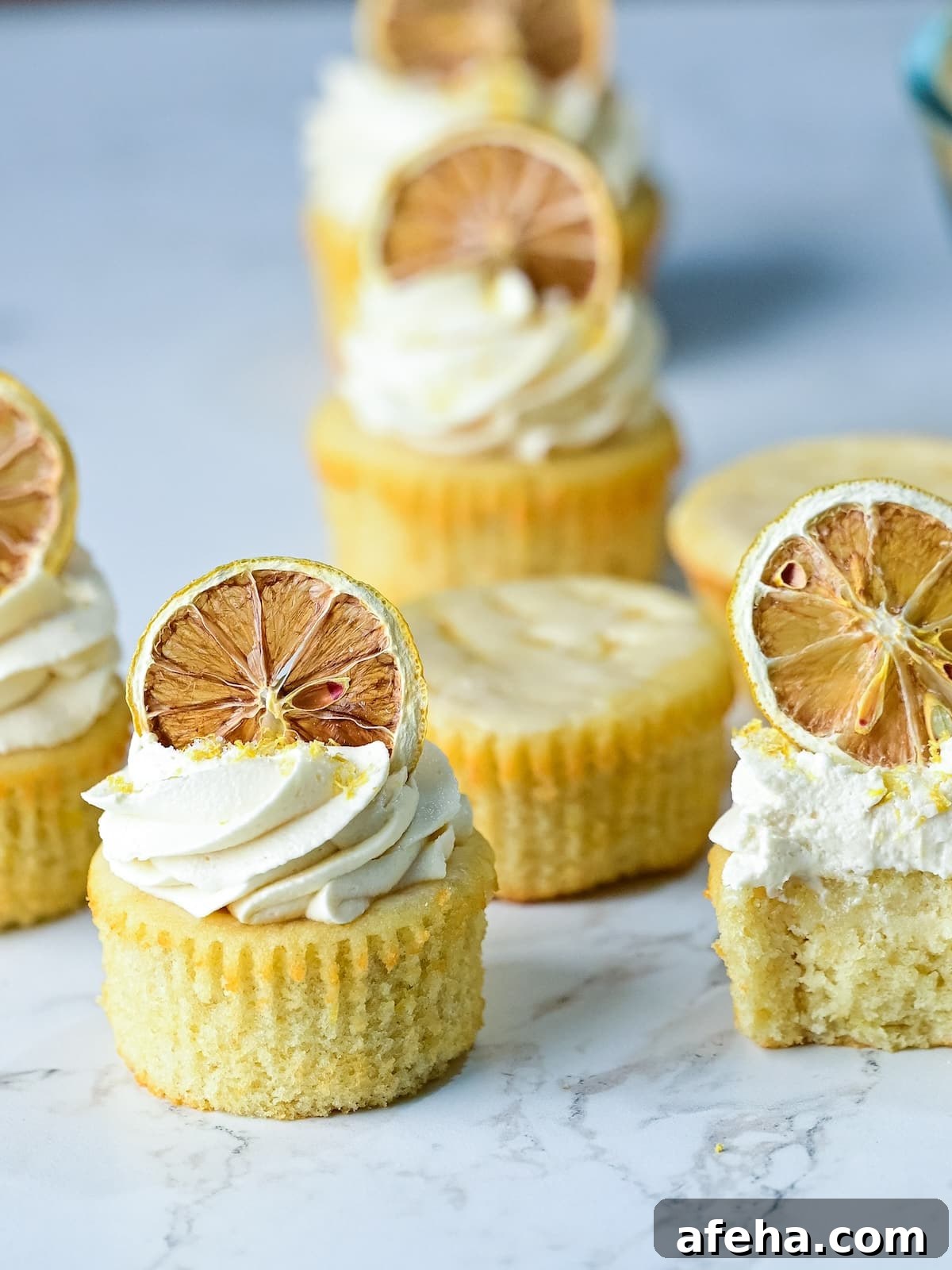 several lemon drizzle cupcakes arranged on a marble surface together.