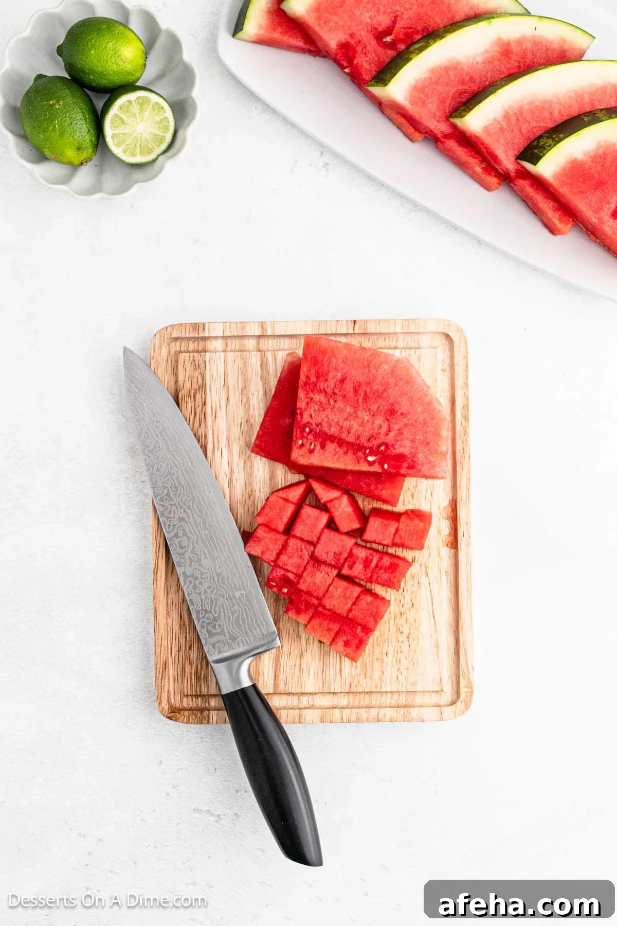 Watermelon cut into cubes on a cutting board.
