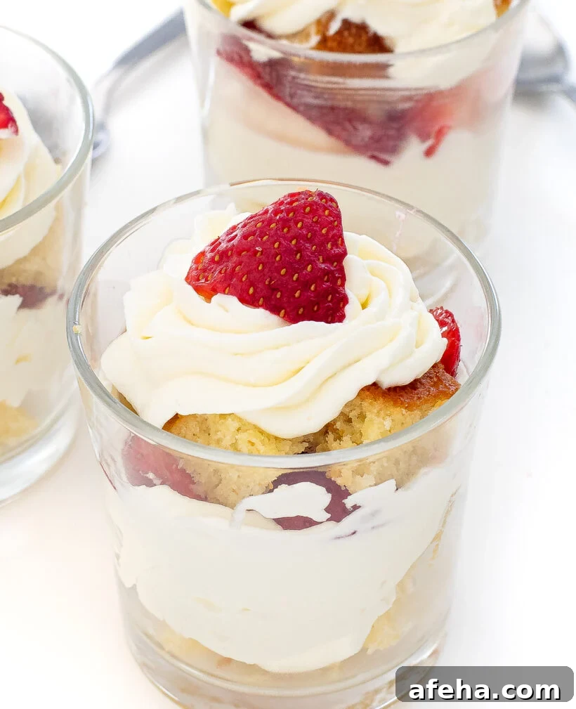 Mini Strawberry Shortcake in a clear glass with layers of cake, cream and strawberries.