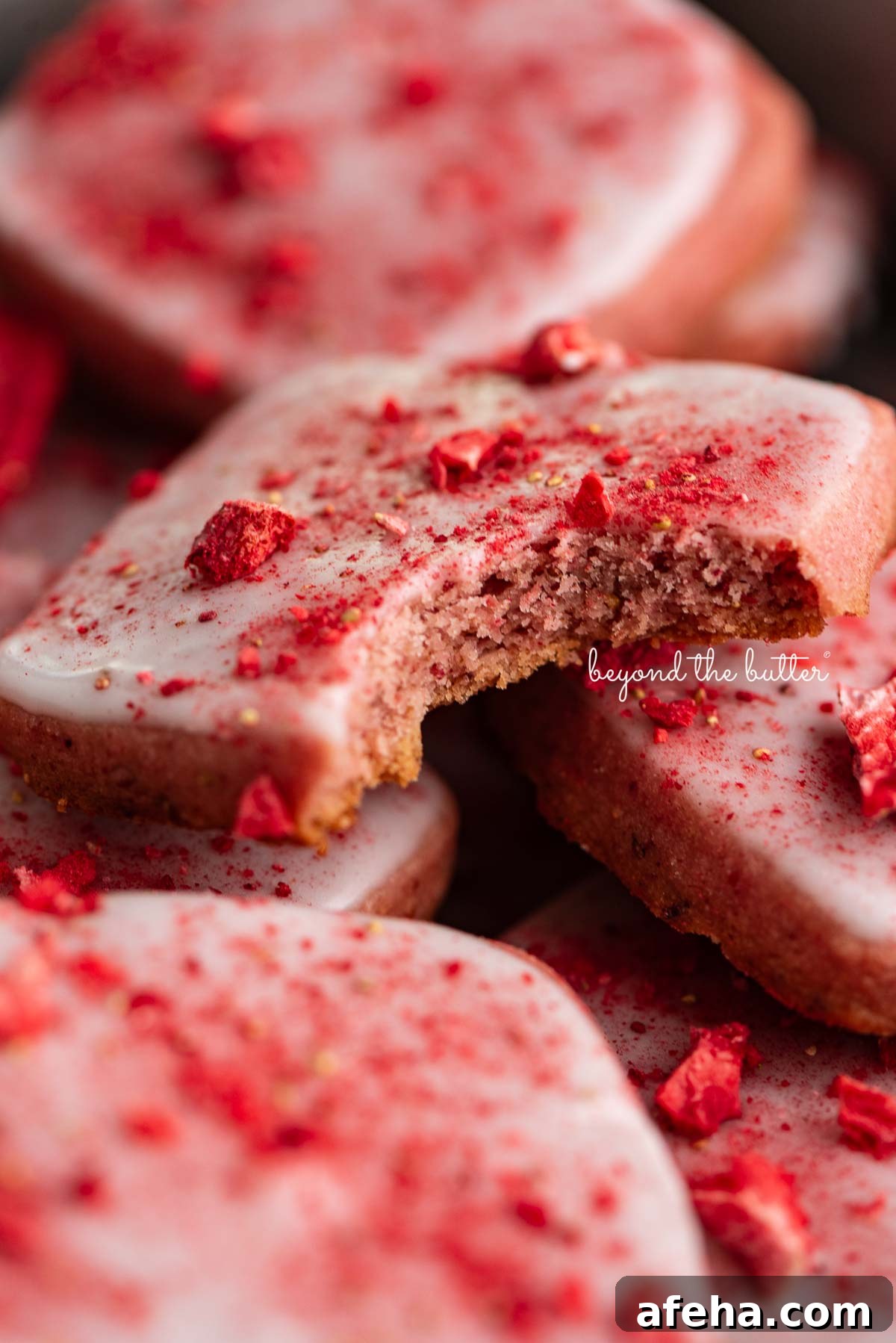 Strawberry shortbread cookies topped with glaze and freeze-dried strawberry bits randomly placed in a vintage baking tin.