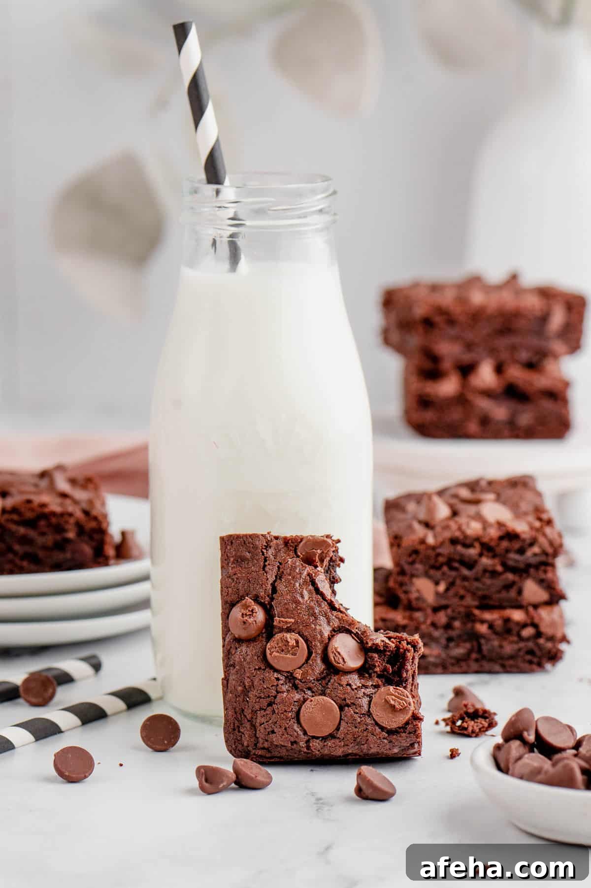 A piece of air fryer brownie with a bite taken out propped against a bottle of milk.