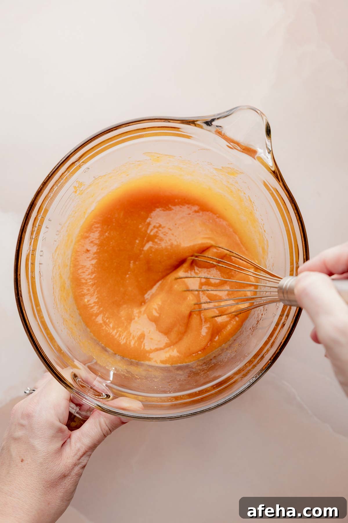 Mixing bowl with pumpkin batter and whisk for gluten free pumpkin bread.