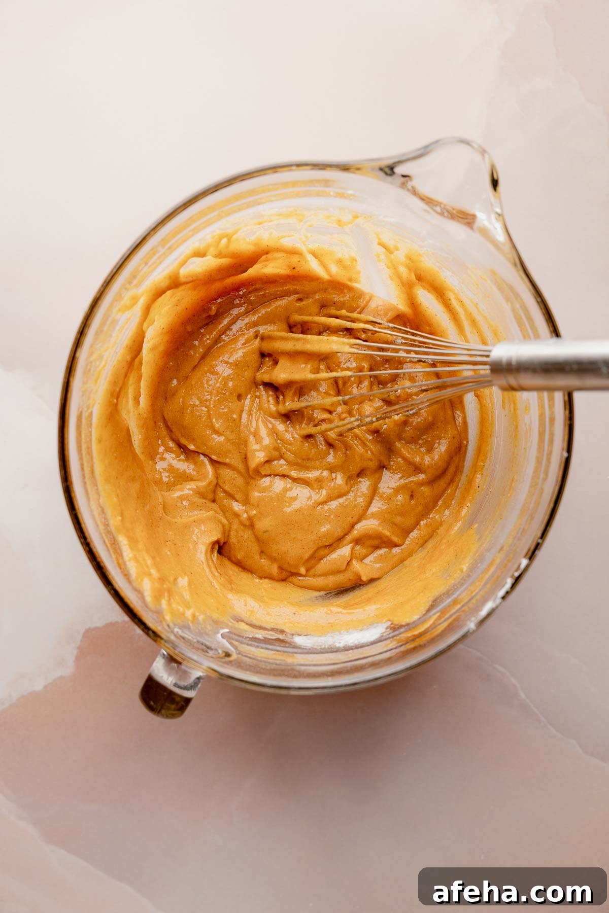 Thicker pumpkin bread batter in mixing bowl with whisk.