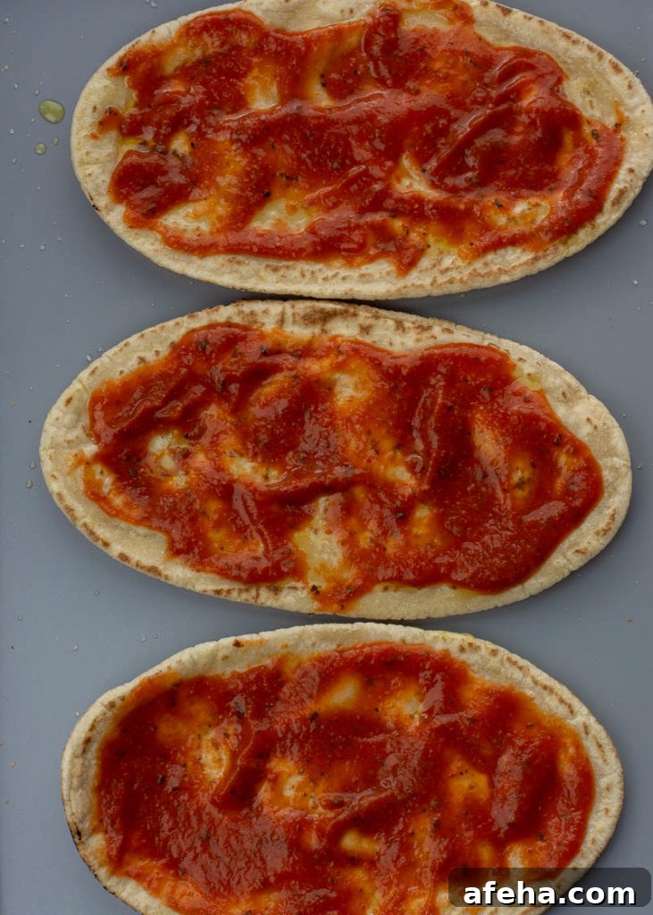 Spreading pizza sauce on pita crust