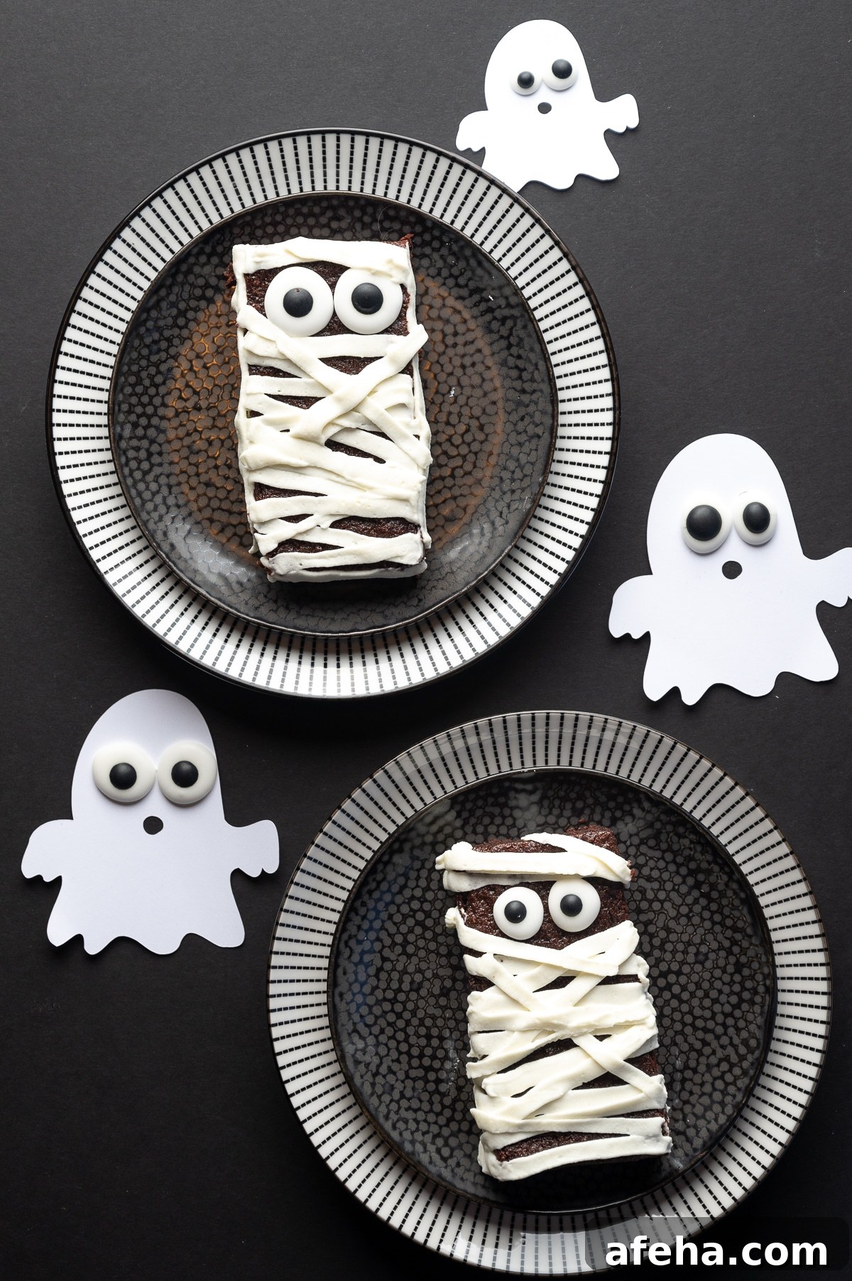 Sugar free brownie with googly eyes and frosting applied in strips to look like bandages on a black background