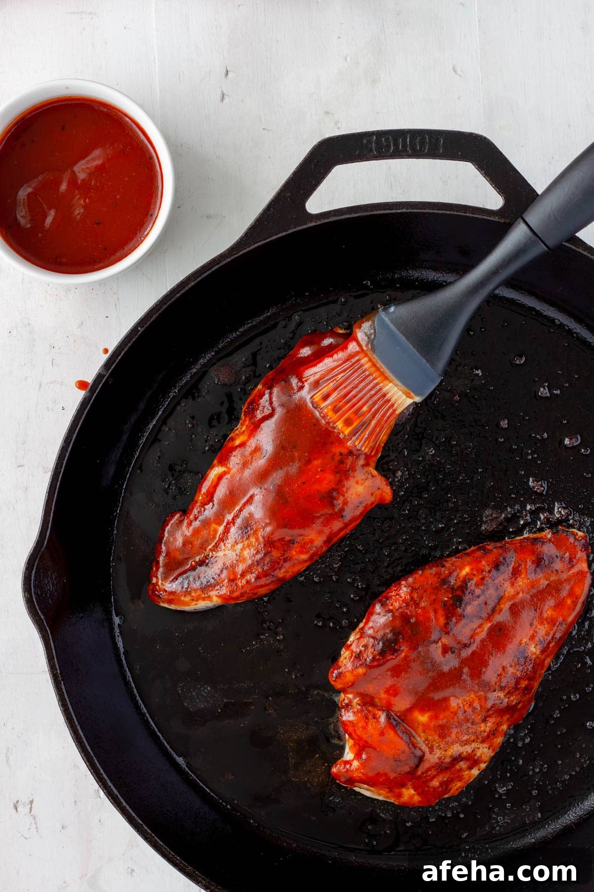 Cast Iron BBQ Chicken Breast Recipe 6 Cast iron BBQ chicken getting brushed with more bbq sauce.