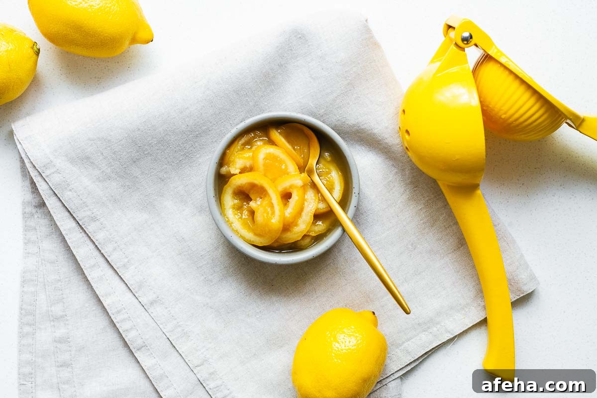 A small ceramic bowl with slices of cheat's preserved lemon with a gold tablespoon surrounded by whole lemons.