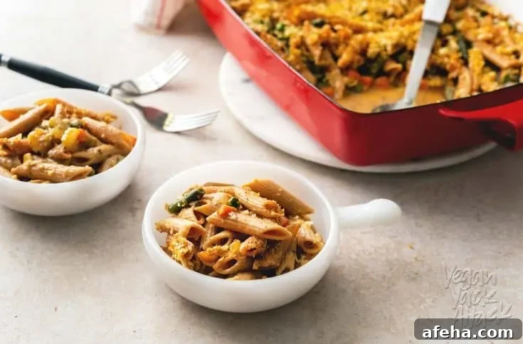 A photo of two bowls filled with vegan noodle casserole, next to a casserole dish.
