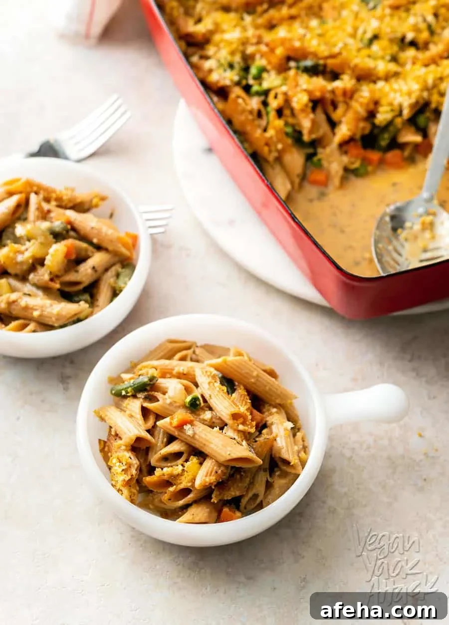 A photo of two bowls filled with vegan noodle casserole, next to a casserole dish.