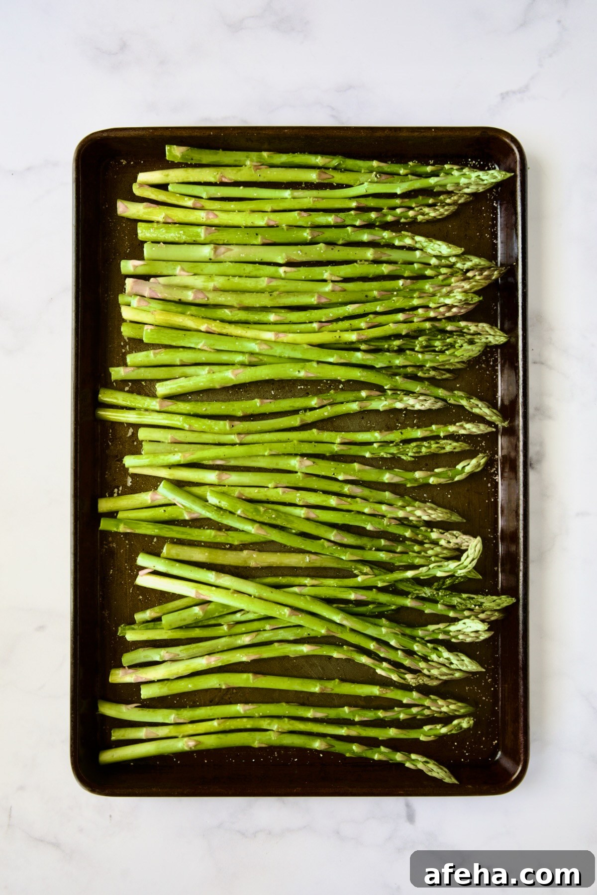 Asparagus on rimmed baking sheet before being roasted.