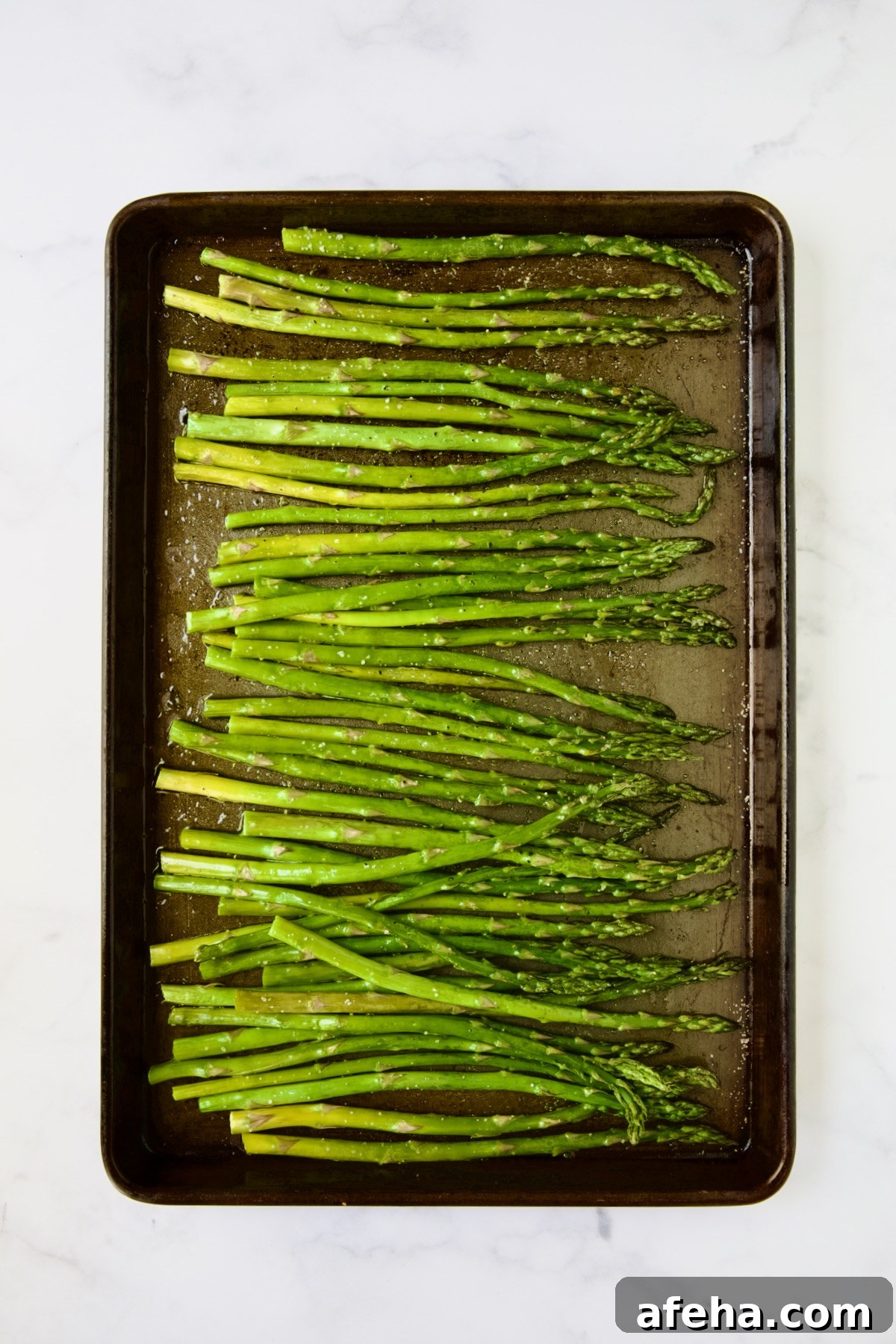 Roasted asparagus on rimmed baking sheet.